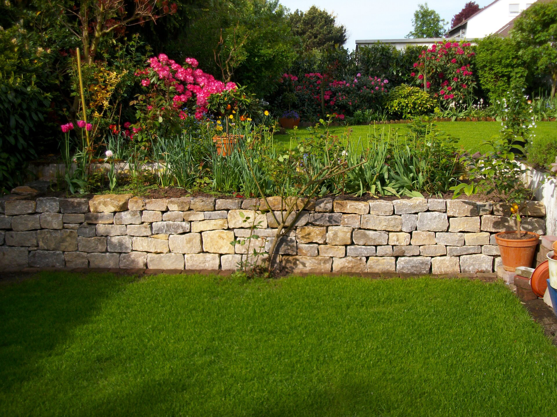 Steingarten mit Blumenbeet und Rasen